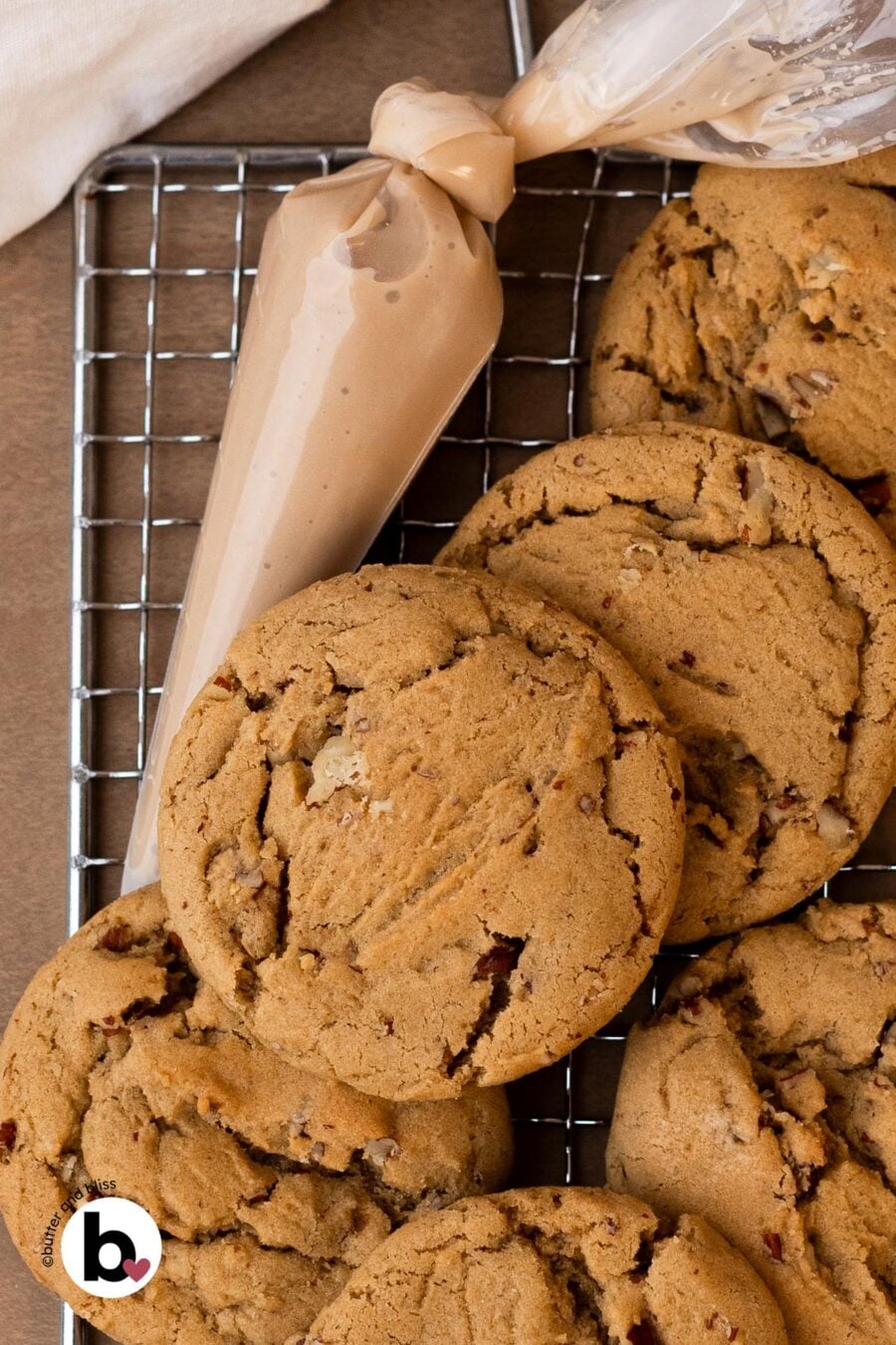 Small batch maple brown sugar cookies stacked on a wire rack next to a piping bag of glaze.