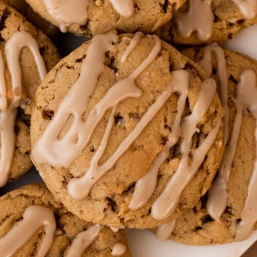 A stack of maple brown sugar cookies with maple icing on a white plate.