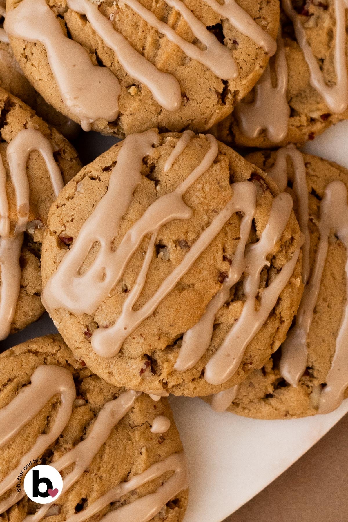 A stack of maple brown sugar cookies with maple icing on a white plate.