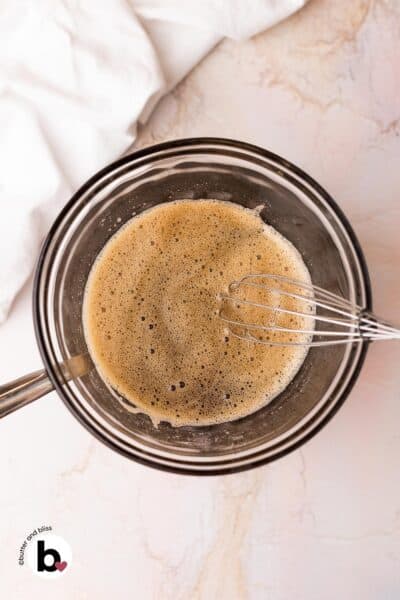 Frothy egg whites and maple syrup in a mixing bowl over a double boiler.