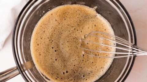Frothy egg whites and maple syrup in a mixing bowl over a double boiler.