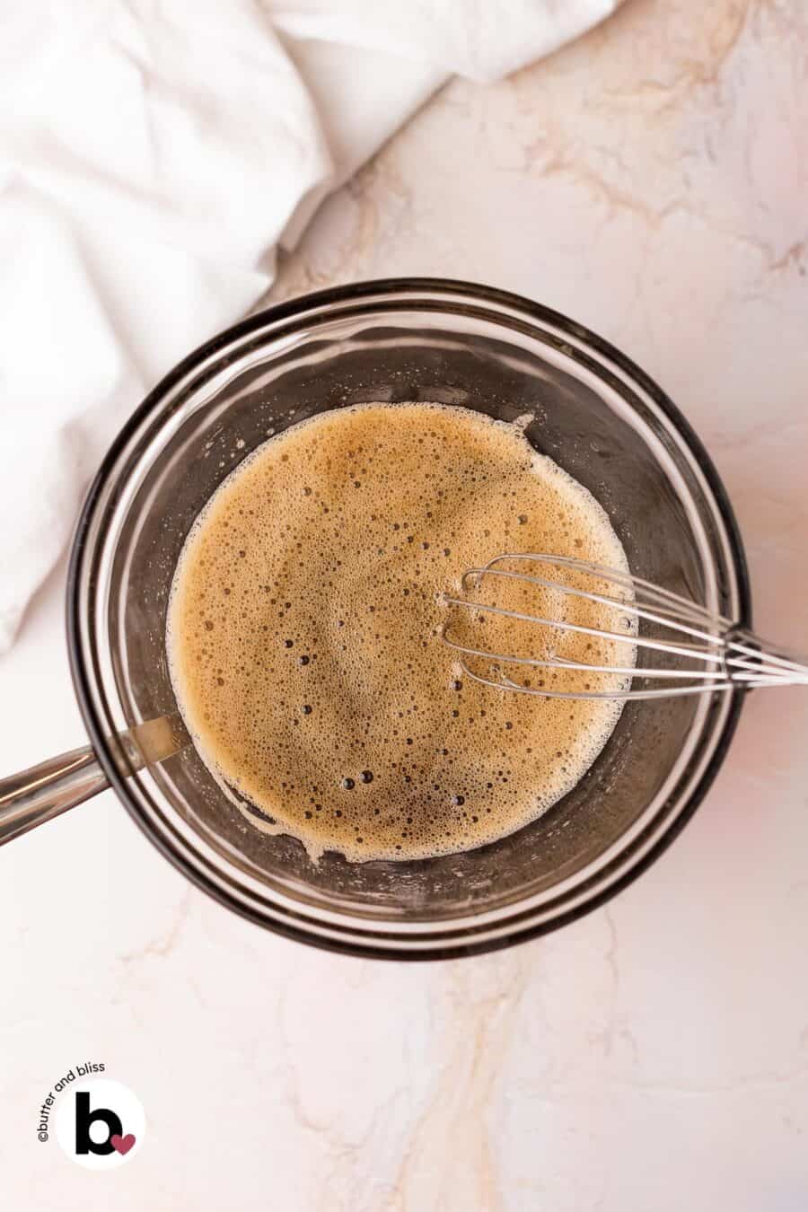 Frothy egg whites and maple syrup in a mixing bowl over a double boiler.