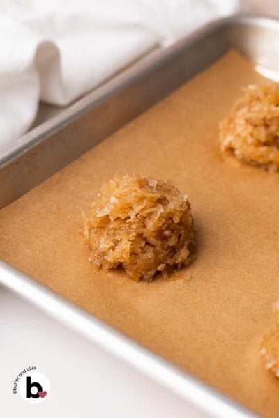Scoop of maple macaroons dough on a parchment lined baking sheet.