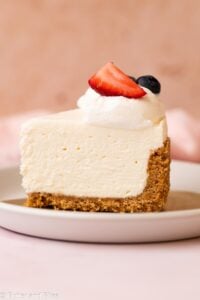 A single slice of creamy no-bake cheesecake topped with fruit on a plate.