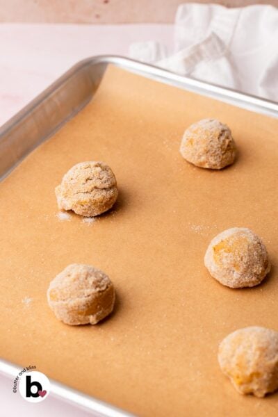 Peanut butter blossom cookie dough balls on a cookie sheet, ready to be baked.