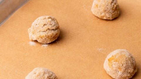 Peanut butter blossom cookie dough balls on a cookie sheet, ready to be baked.