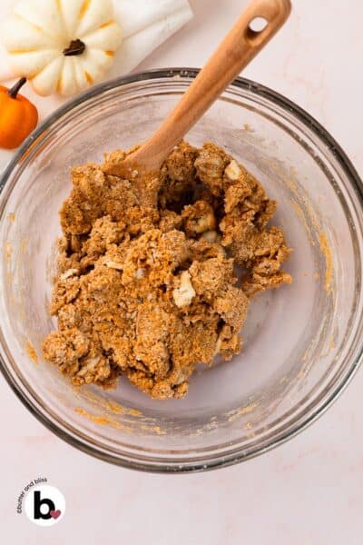 Shaggy pumpkin spice scones dough in a mixing bowl with a wooden spoon.