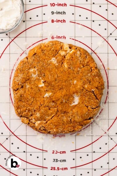 6-inch disc of pumpkin spice scones dough on a rolling mat.