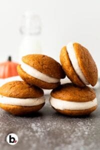 Small batch pumpkin whoopie pies stacked on top of eachother next to a jar of milk.